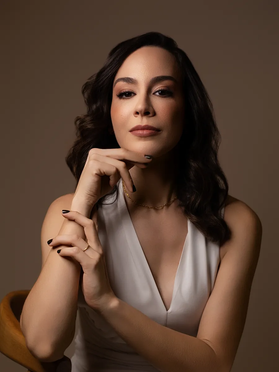 Dra. Rafaela Marques, cirurgiã plástica, em retrato com a mão sob o queixo, de blusa branca