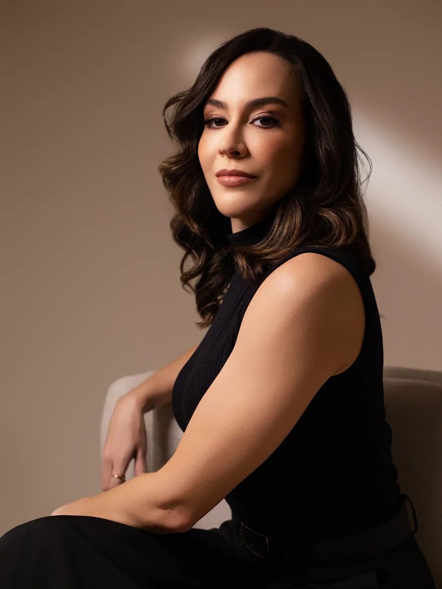 Dra. Rafaela Marques, cirurgiã plástica, em retrato sentada, de blusa preta
